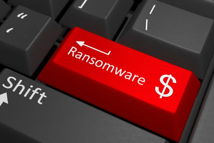 Red keyboard key labeled Ransomware with a dollar sign. Surrounding keys are gray. Represents cyber threats and financial impact.